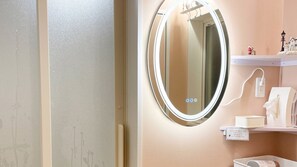 Une salle de bain avec un miroir rond, un porte-serviettes et une étagère contenant des articles de toilette.