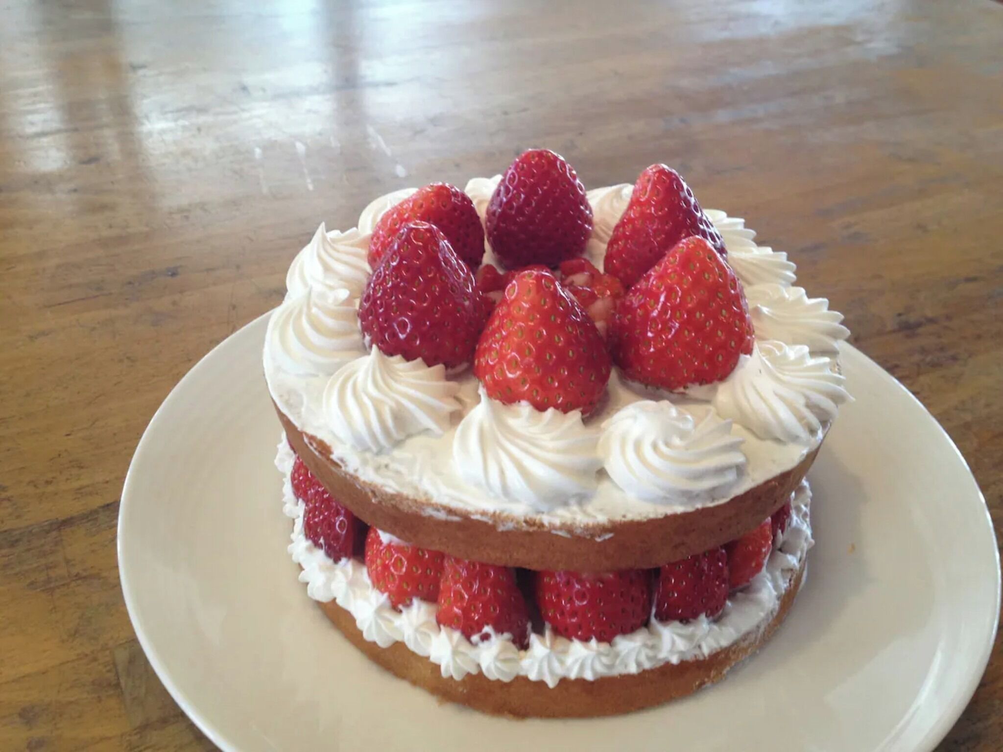 A layered dessert cake with strawberries and whipped cream on a plate.