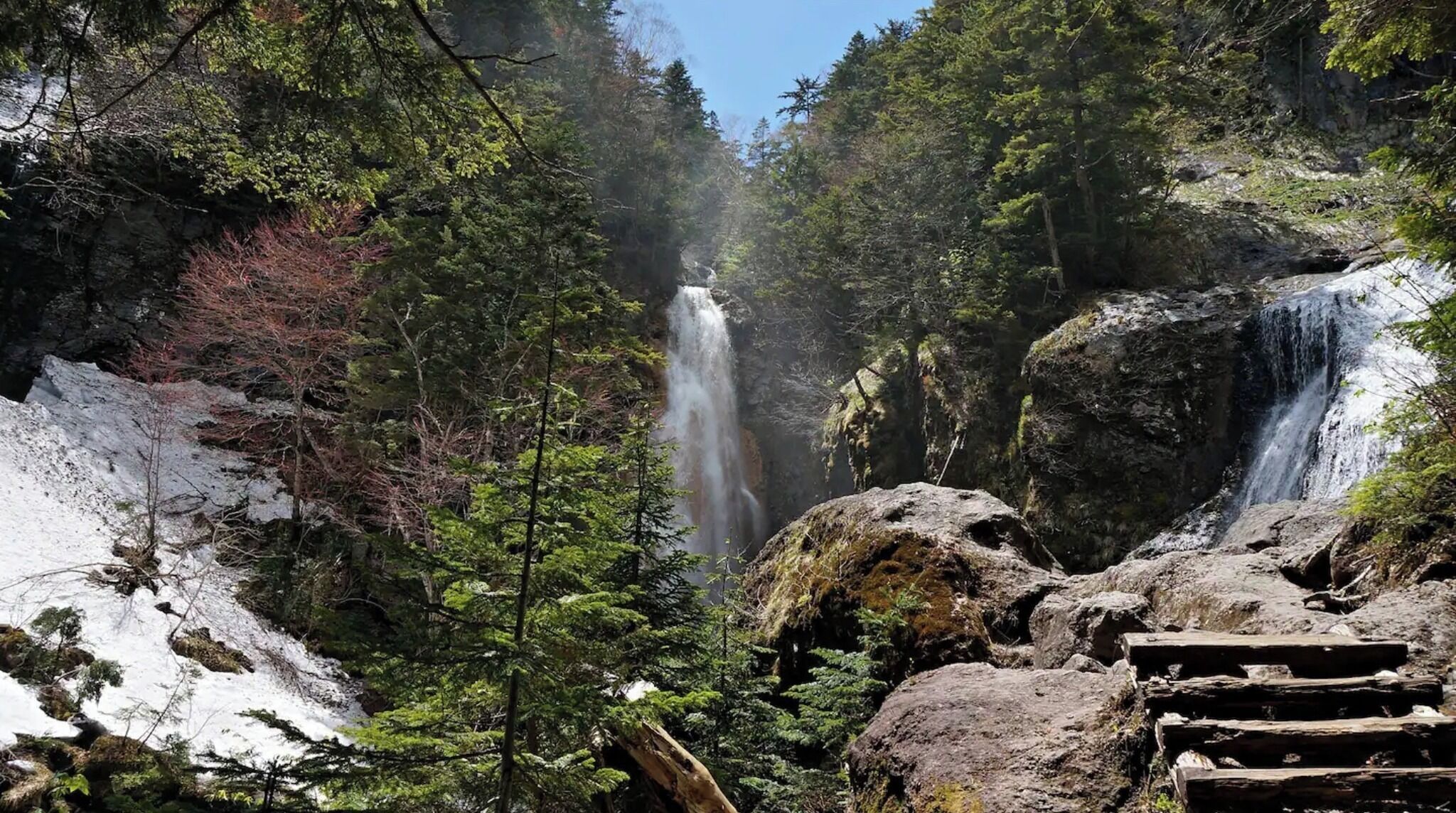 A forested area with two waterfalls and a rocky terrain.
