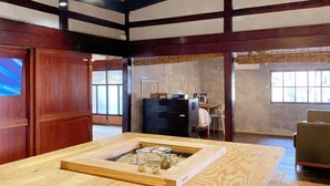 Um quarto japonês tradicional com tatames, uma mesa de madeira baixa com uma estrutura de vidro e uma porta de madeira deslizante.