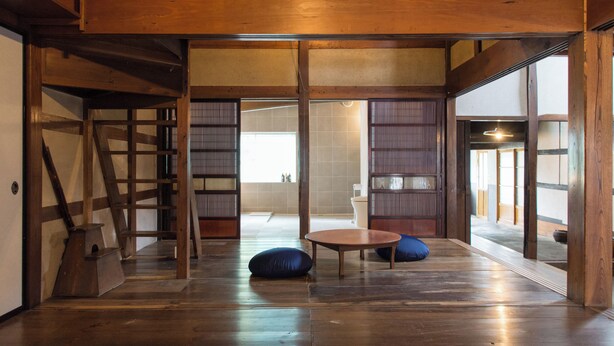 Um quarto japonês tradicional com tatames, portas deslizantes e uma mesa de madeira baixa com almofadas.