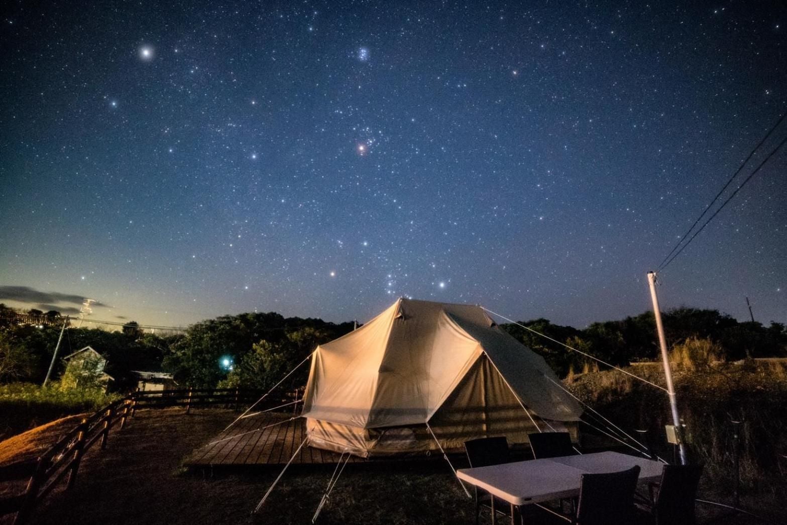 A tent set up outdoors with a clear night sky above.