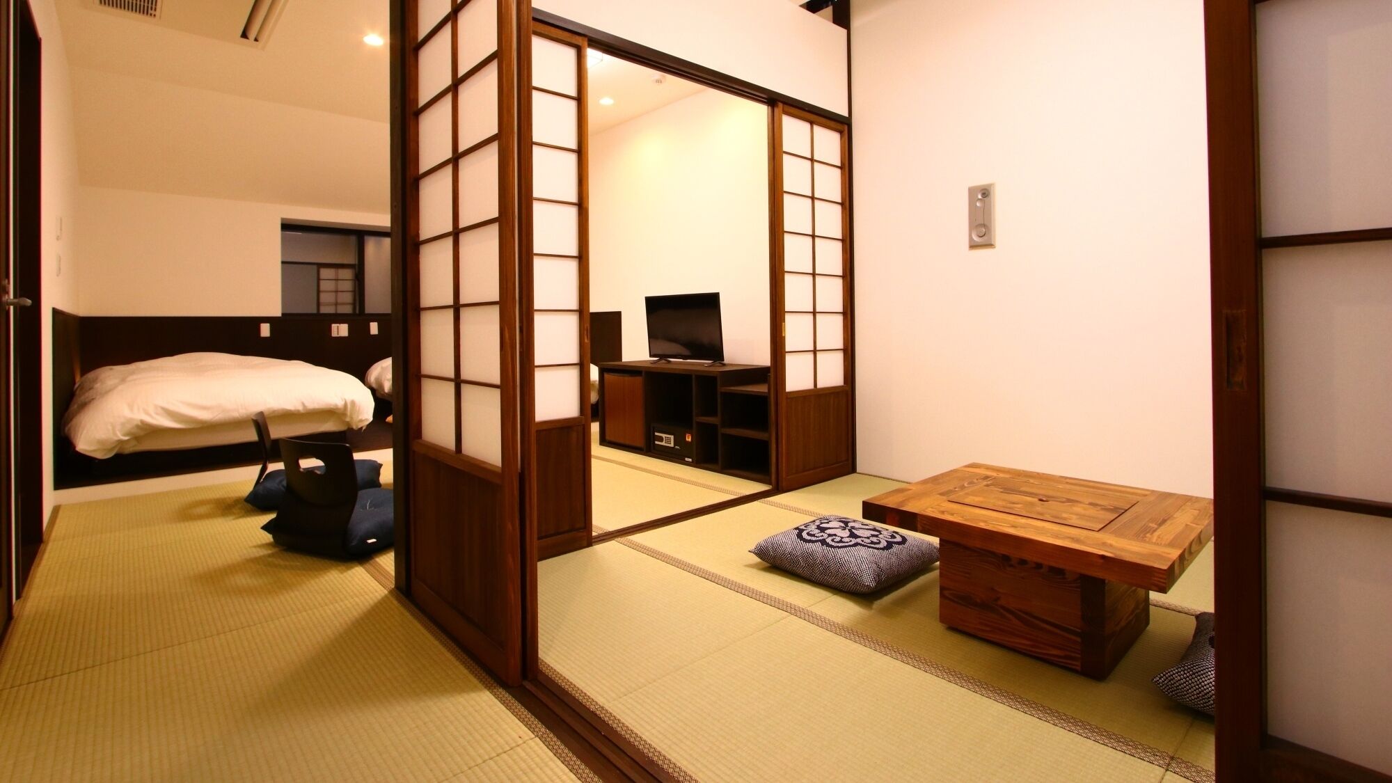 Een traditionele Japanse kamer met tatami vloeren, een futon bed, een televisie en een houten tafel.
