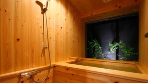 Un sauna en bois doté d’une fenêtre, d’une pomme de douche et d’un banc en bois.
