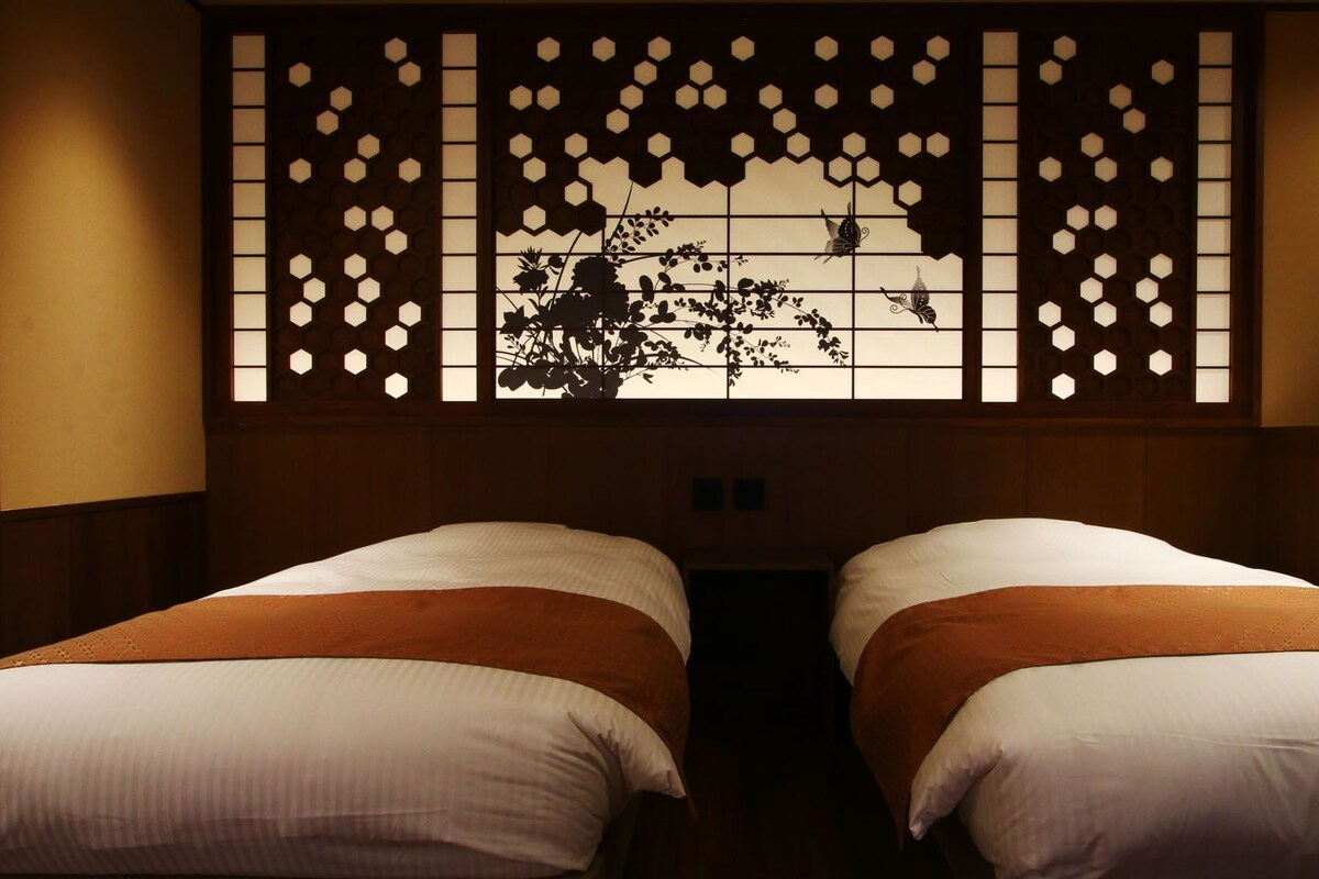 A room with two beds, a decorative wall with hexagonal patterns, and a wooden headboard.
