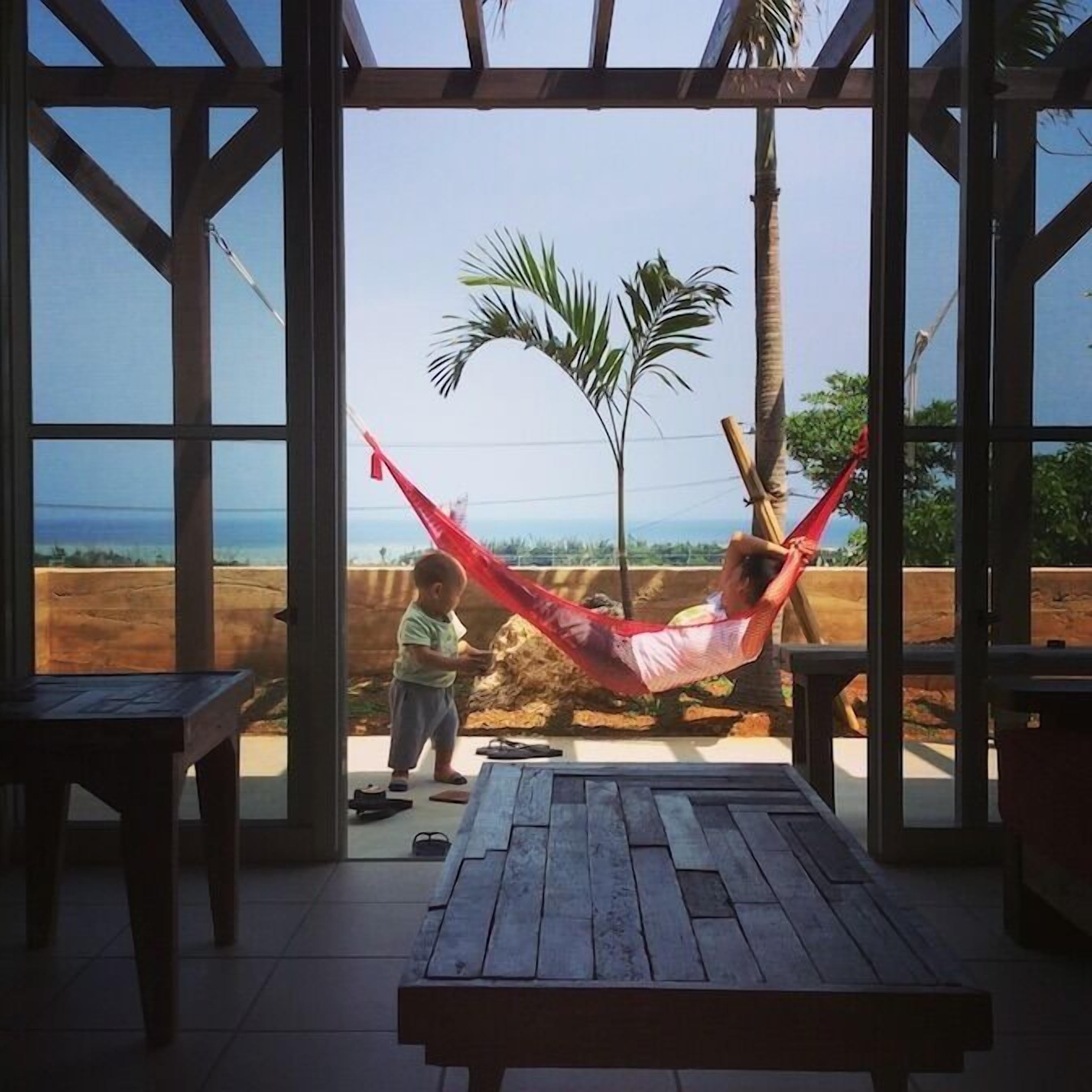 A wooden pergola with a hammock and a child playing outside.