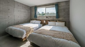 A bedroom with two beds, a large window with curtains, and a concrete wall. - Okinawa Plaisant Villa (Onna)