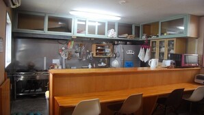 Een keuken met een houten aanrecht, stoelen, een koelkast en een magnetron.