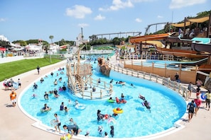Een waterpark met een groot zwembad, glijbanen en een houten speelconstructie.