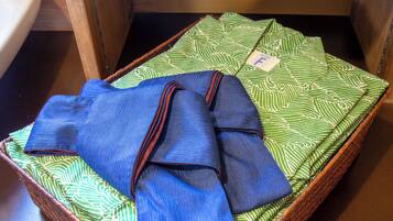 Una prenda azul doblada con cuidado sobre una tela verde estampada dentro de una cesta de mimbre.