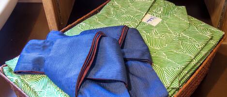 Una prenda azul doblada con cuidado sobre una tela verde estampada dentro de una cesta de mimbre.