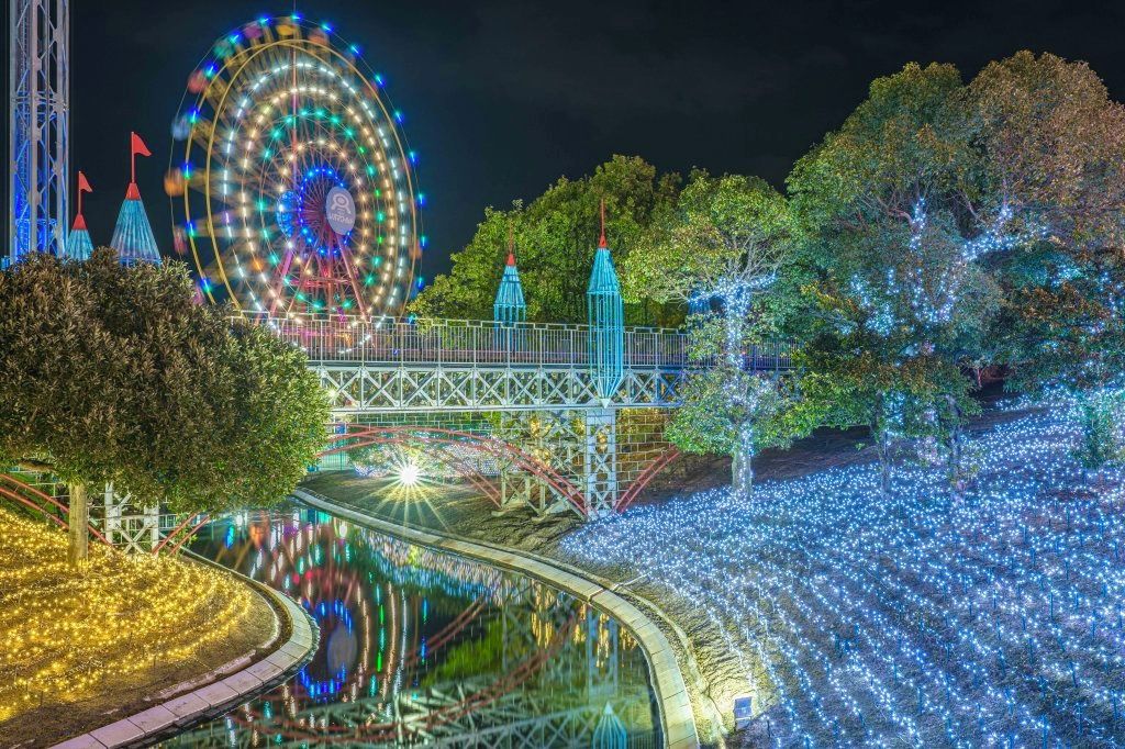 A Ferris wheel, a bridge, and trees with lights.