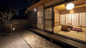 Une pièce de style japonais traditionnel, avec un sol recouvert de tatamis, une petite table en bois et une porte coulissante.