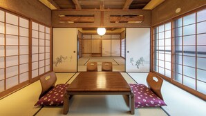 Une pièce de style japonais traditionnel, avec un sol recouvert de tatamis, des paravents en papier de riz (shoji) et une basse table en bois entourée de coussins.