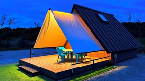 A modern, triangular-shaped building with a wooden deck and outdoor seating area. - Glamping Cottage Liberty Resort Daito Onsen (Kakegawa)