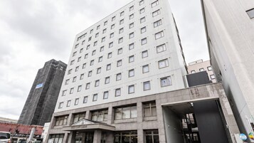 Un hotel de varios pisos con una fachada moderna, que cuenta con una entrada destacada y un cartel que indica que es un hotel.