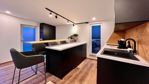 A modern kitchen with a central island, bar stools, and a built-in sink. - Ferienwohnung mit schöner Terrasse in Bad Lausick (Bad Lausick)