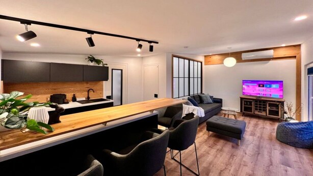 A modern kitchen with a wooden countertop, black chairs, and a dining area. - Ferienwohnung mit schöner Terrasse in Bad Lausick (Bad Lausick)