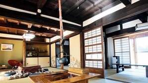 Una stanza tradizionale giapponese con pavimento in tatami, un tavolo di legno, una teiera appesa e porte scorrevoli.