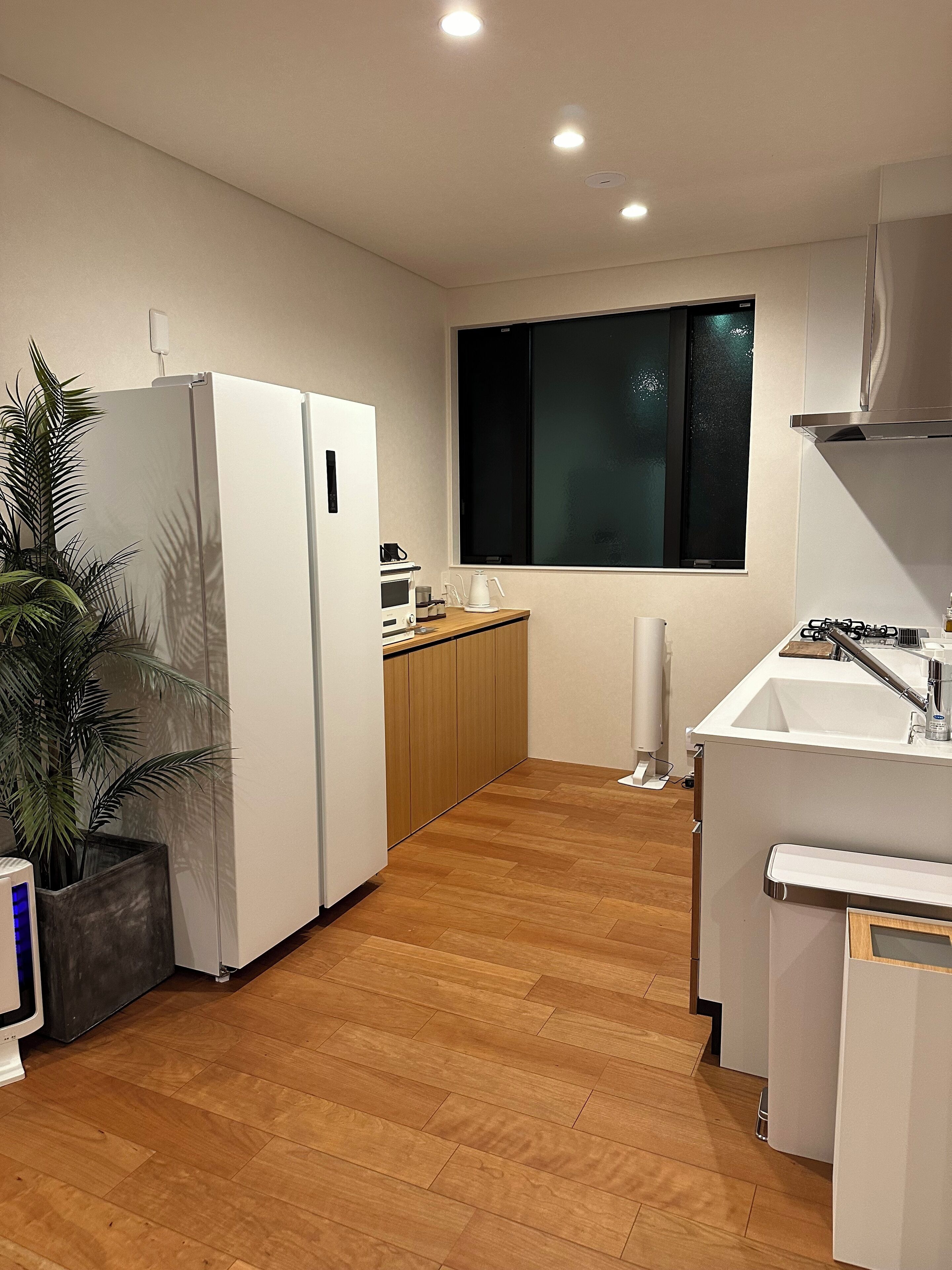 Une cuisine moderne équipée d’un réfrigérateur, d’un four à micro-ondes, d’un évier et de meubles de rangement en bois.