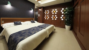 A hotel room with a large bed, a wooden headboard, a wall with circular light fixtures, and a potted plant. - Tatami no Yado Chatan Mihama by Coldio Premium (Chatan)