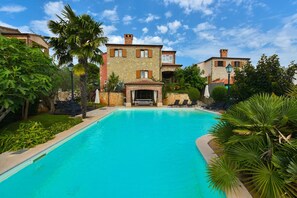 A swimming pool with a stone building in the background, surrounded by lush greenery. - Villa mit Pool in Kaštelir für 9 Personen (Kaštelir)