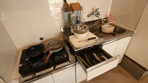 A kitchen with a stove, sink, and various utensils.