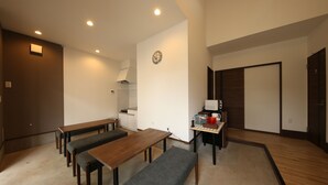 A modern living room with a dining area, a kitchen, and a wooden floor.