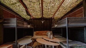 Een kamer met stapelbedden, een slaapbank, een ronde tafel en een vloer met een patroon.