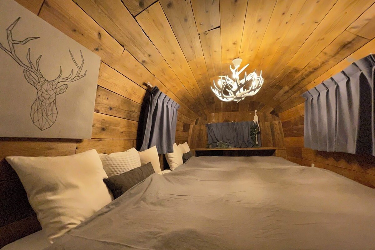 Een gezellig houten kamer met een groot bed, een plafondlamp en een kunstwerk van een hertenkop aan de muur.