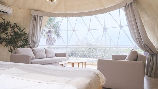 Een ruime kamer met een groot bed, twee banken en een eettafel.