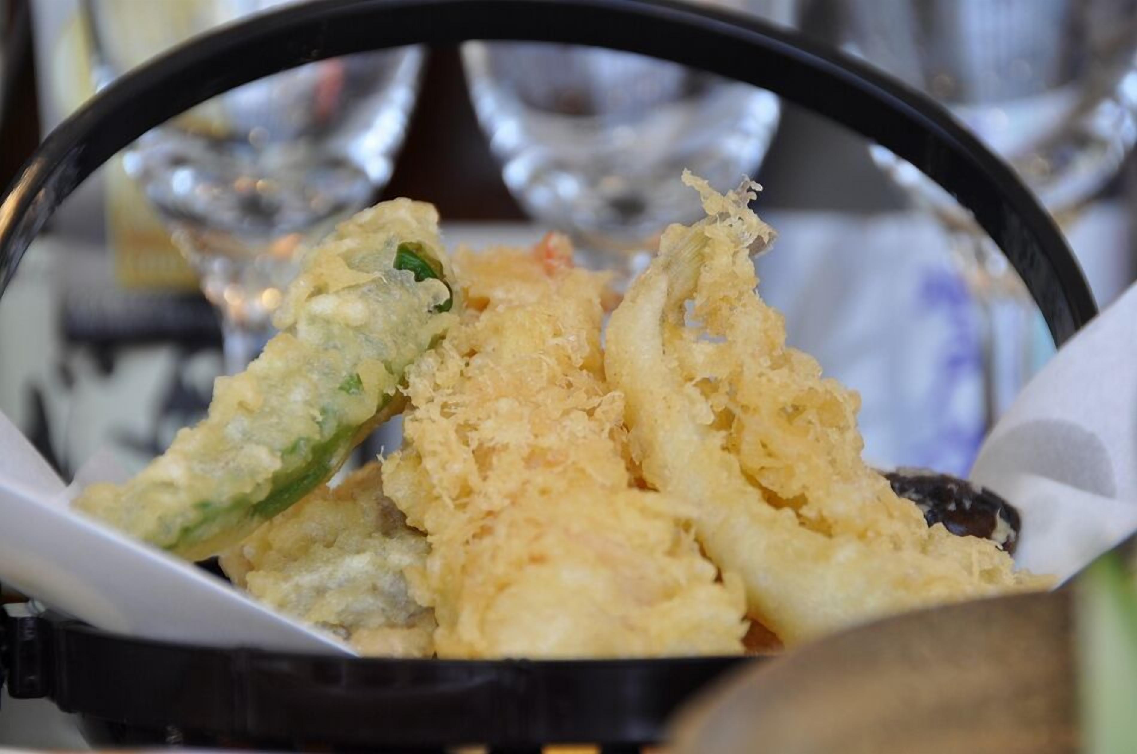 A basket of fried food items, likely tempura, with a focus on the crispy texture and golden color.