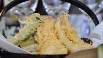 A basket of fried food items, likely tempura, with a focus on the crispy texture and golden color.