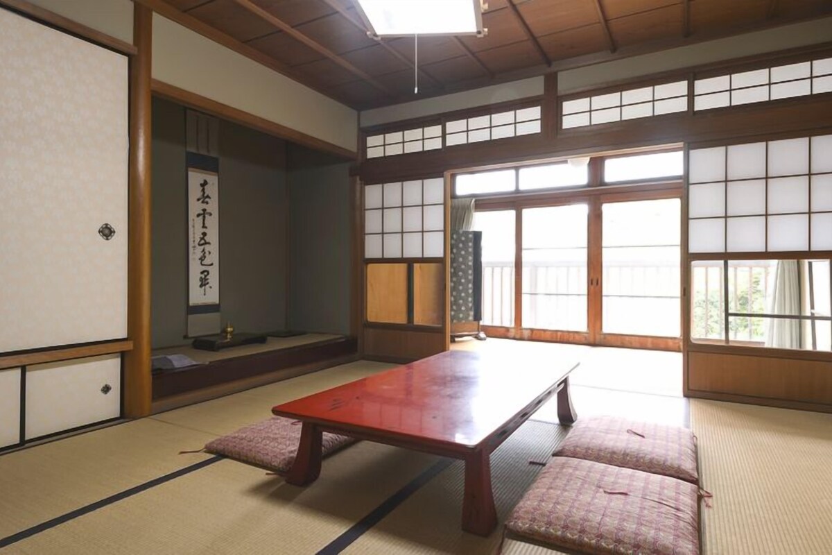 A traditional Japanese room with tatami flooring, a low wooden table, sliding doors, and a shoji screen.