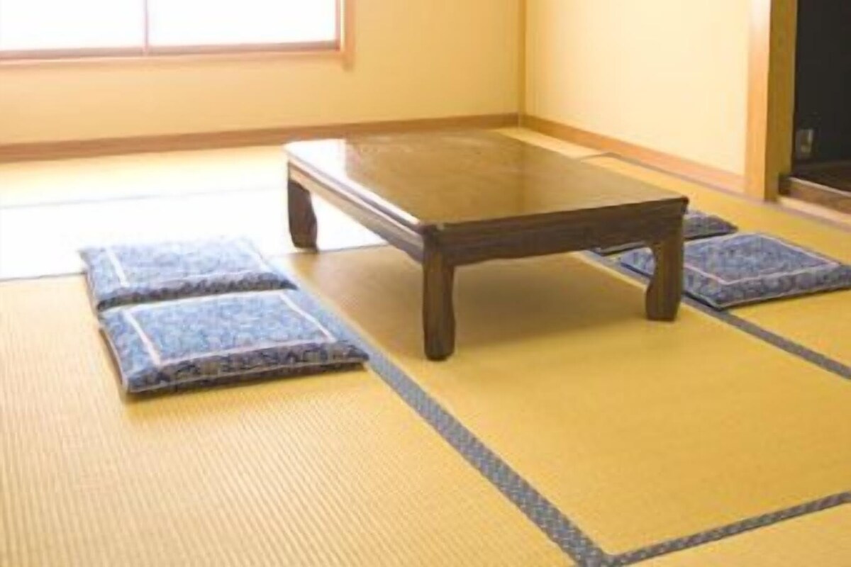 A traditional Japanese room with tatami flooring, a low wooden table, and a sliding door.