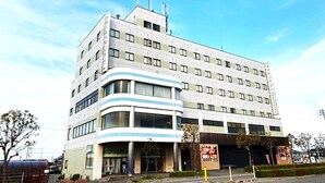 Un edificio de varios pisos con una entrada curva, grandes ventanales y un cartel.