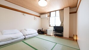 Een kamer met twee bedden, een televisie, airconditioning en een raam met gordijnen.