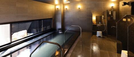 Un spa moderne doté d’une piscine chauffée, d’un sauna et d’un espace douche séparé.