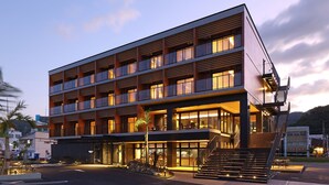 Un hôtel à plusieurs étages au design moderne, doté de balcons, de grandes fenêtres et d’un escalier menant à l’entrée.
