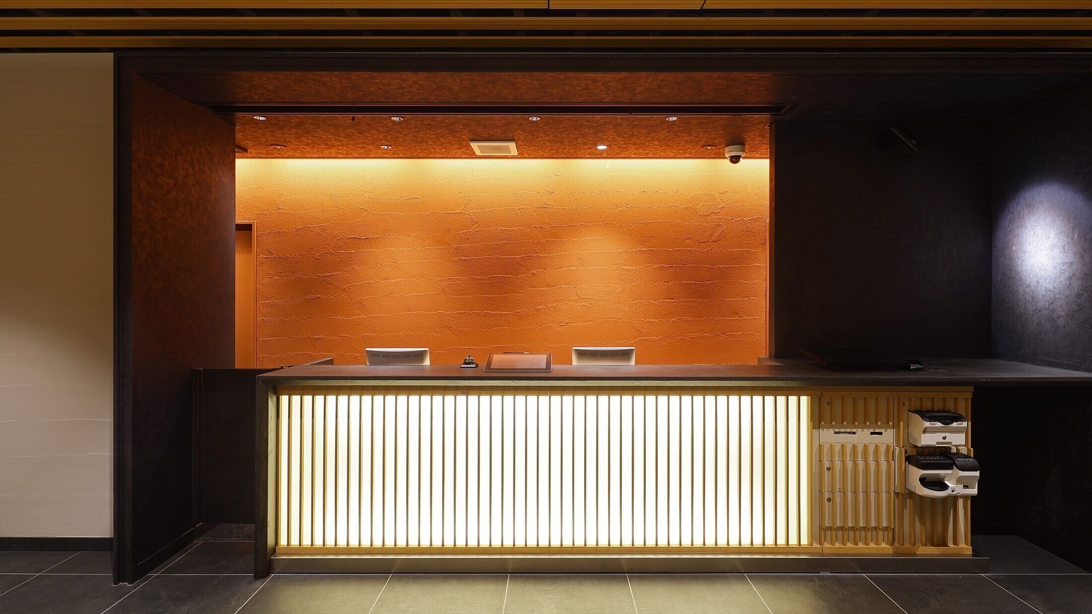 A reception desk with a wooden finish and a vertical light panel.