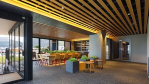 Un intérieur moderne avec un bar, des espaces pour s’asseoir et de grandes fenêtres offrant une vue panoramique.