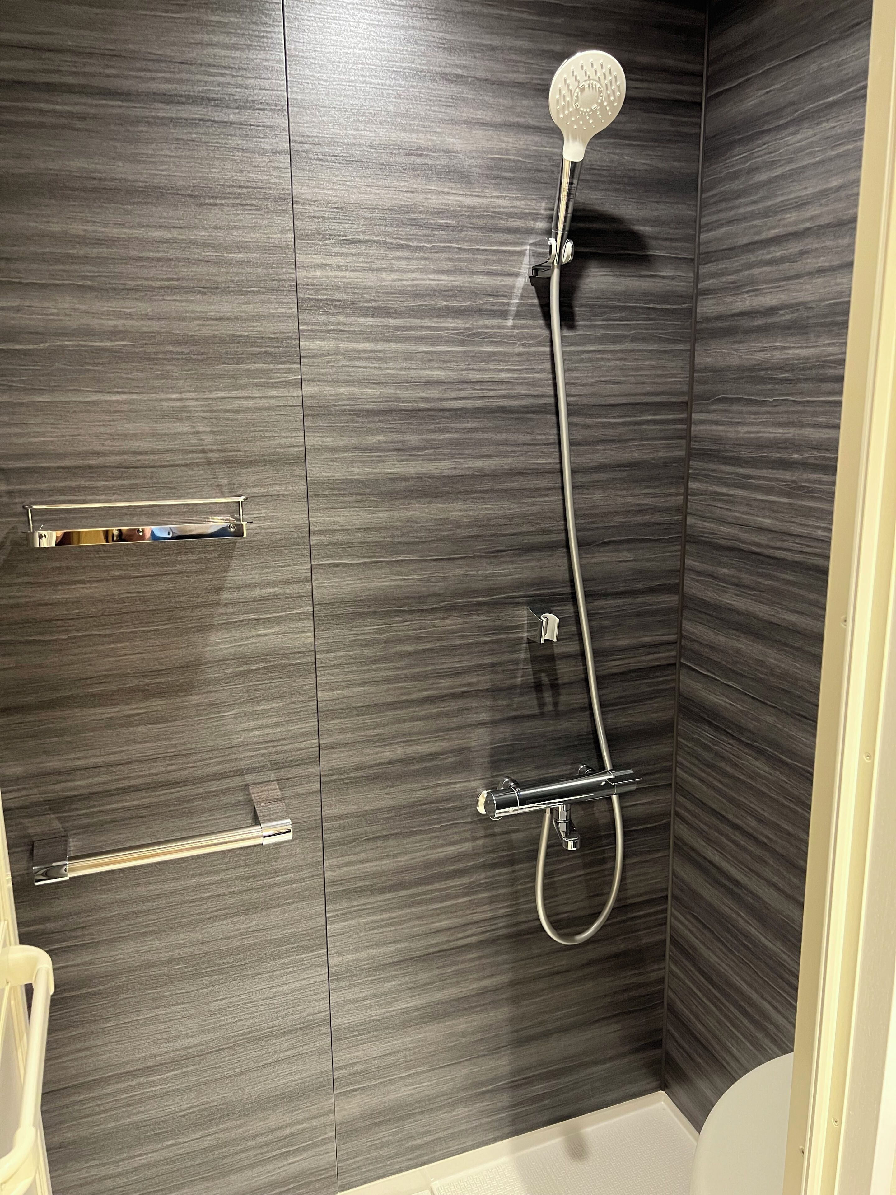A modern bathroom with a shower, a towel rack, and a toilet.