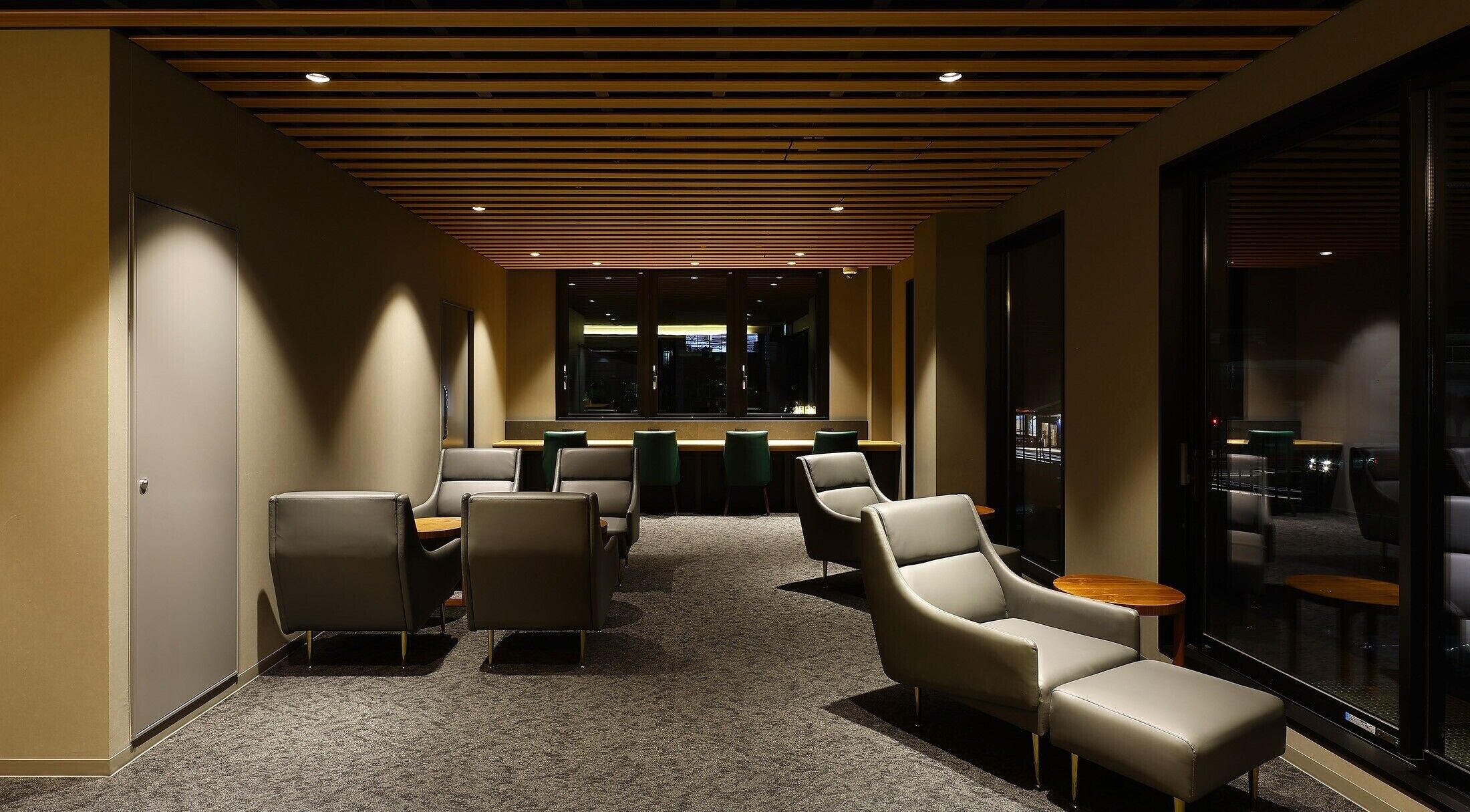 A modern conference room with a long table, several chairs, and a carpeted floor.