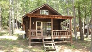 Eine Holzhütte mit Veranda und einer Leiter, die zum Eingang führt.