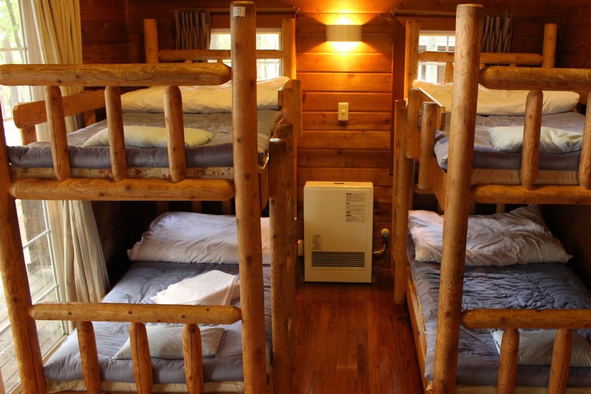 Une cabane avec des lits superposés, des murs en bois et un chauffage central.