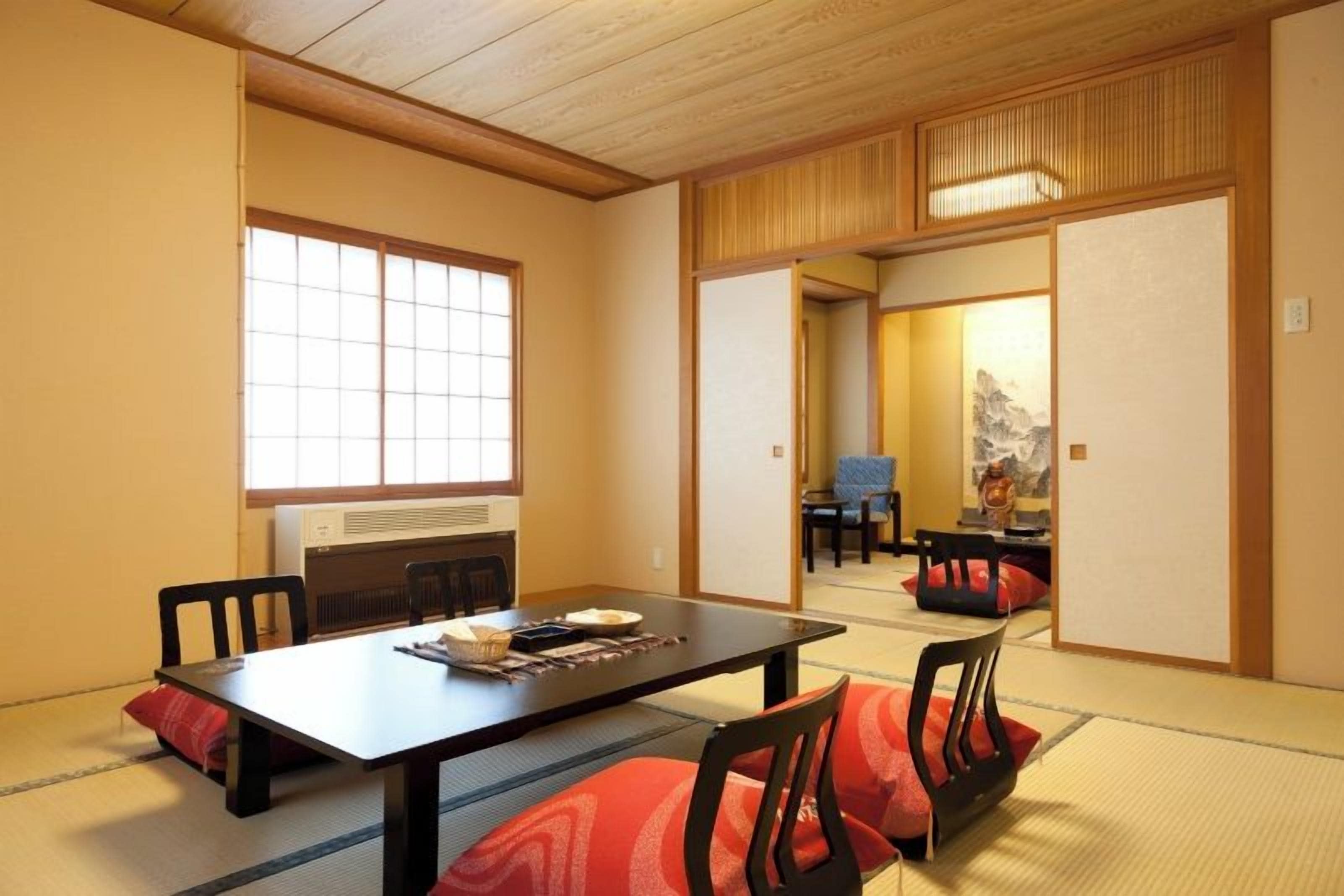 Una habitación de estilo japonés tradicional con suelo de tatami, una mesita baja y una puerta corrediza.