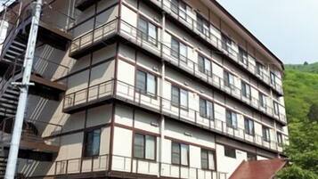 Un edificio de varios pisos con fachada plana, múltiples ventanas y una entrada visible con puerta y escalones.