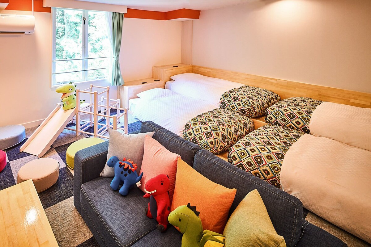 A children's room with a bunk bed, play area, and colorful cushions.