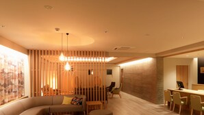 Un salon moderne avec un canapé d’angle, des poufs ronds et un coin repas comprenant des chaises et une table.