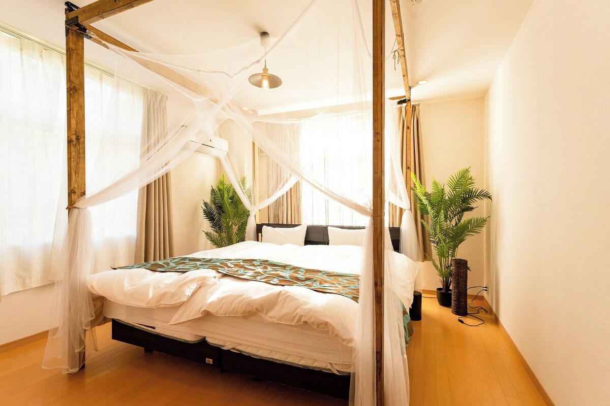 A four-poster canopy bed with a white bedspread and a decorative throw.